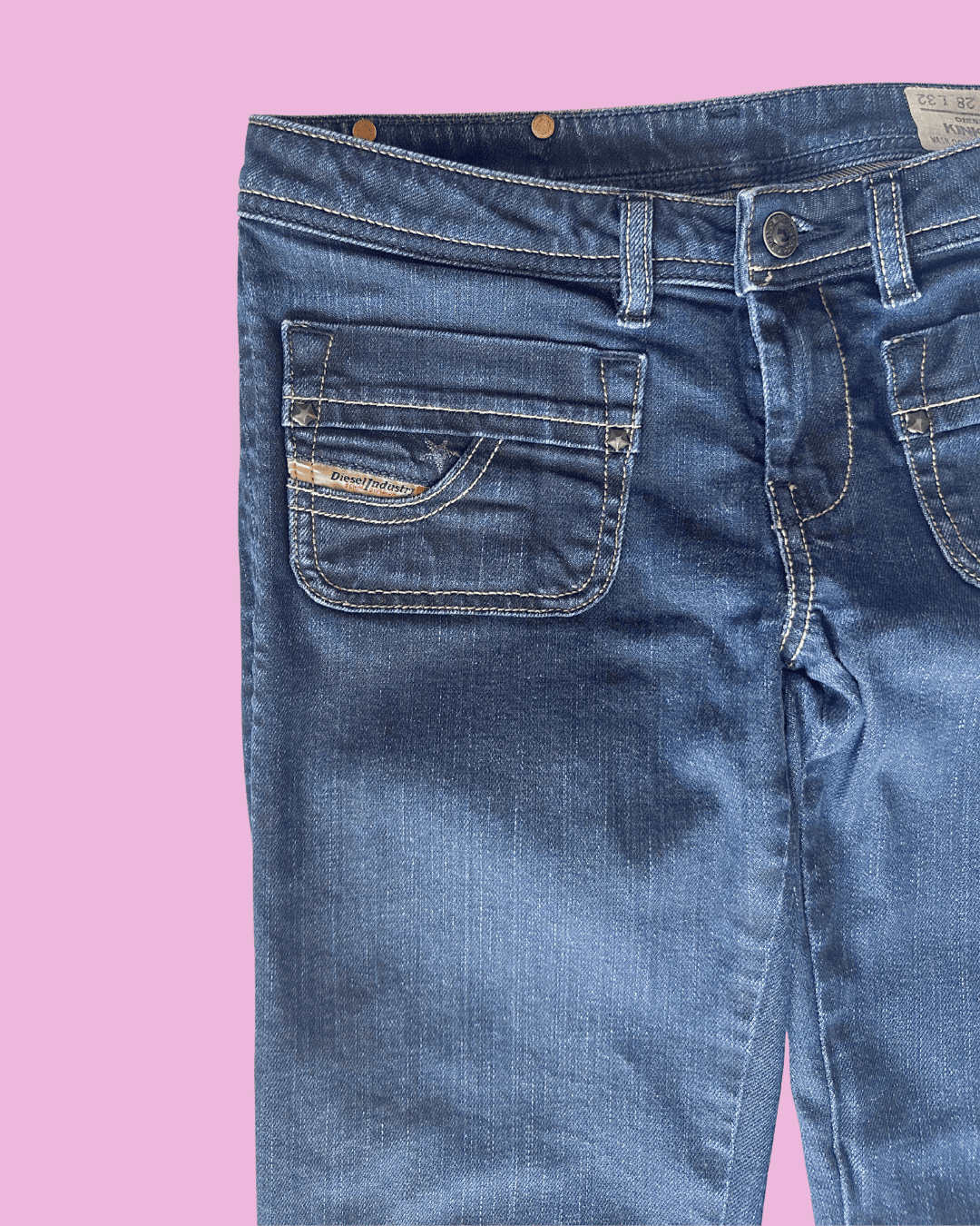 Original close-up of dark denim jeans showing the waistband, button, belt loops, contrast stitching and front flap pocket